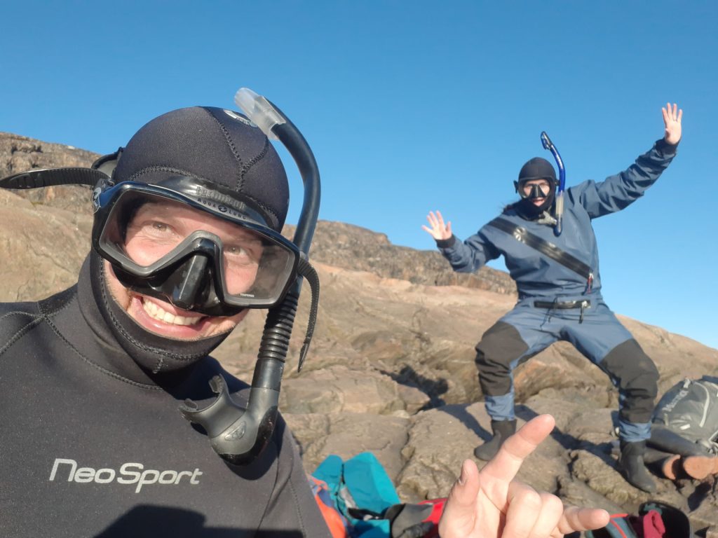 Two divers on rocky shoreline