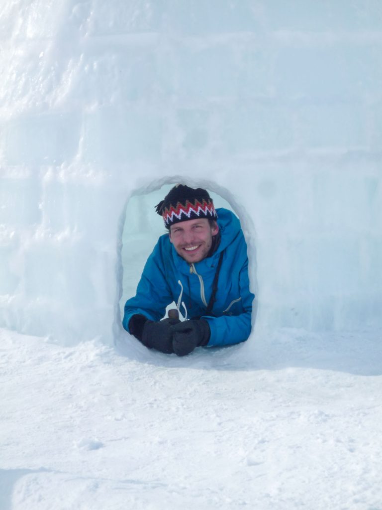 Person smiling from igloo entrance
