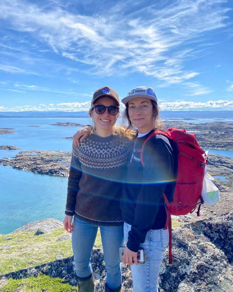 Two women smiling by the water.