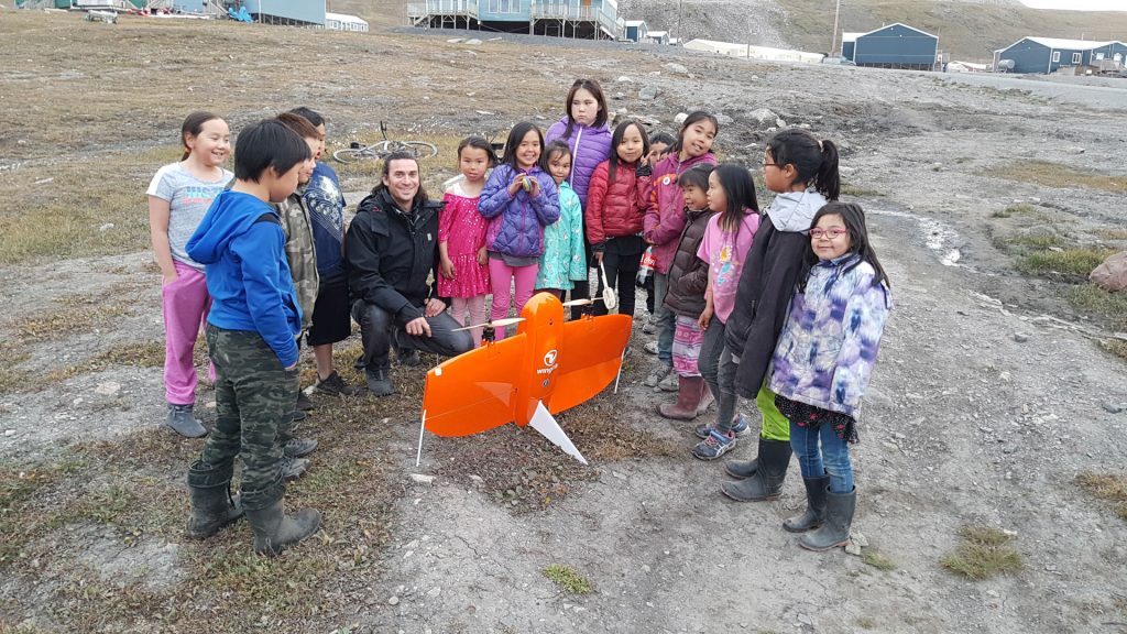 Children gathered around an orange drone.