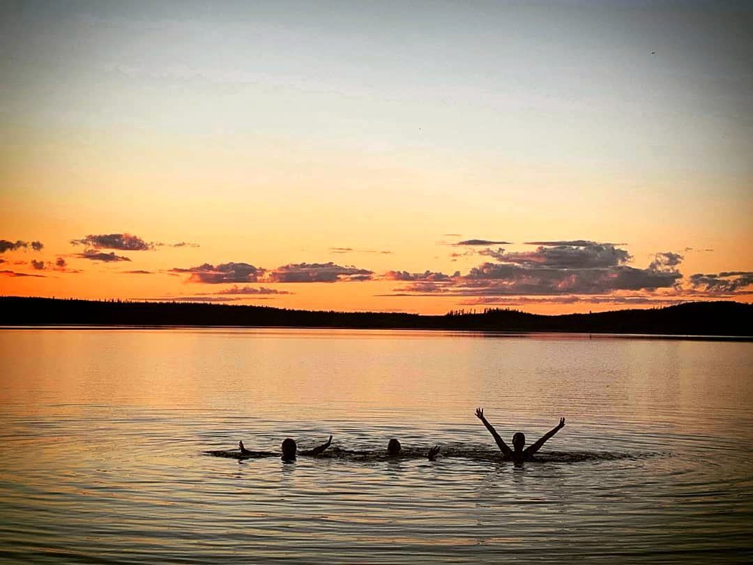 People swimming at sunset.
