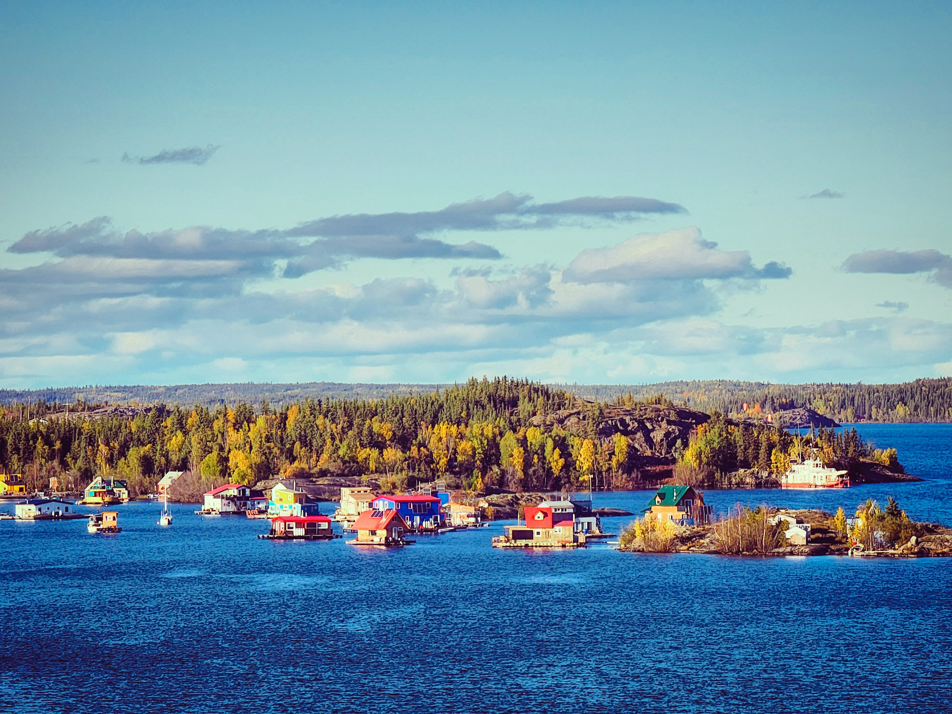 Colorful houses on water surrounded by trees.