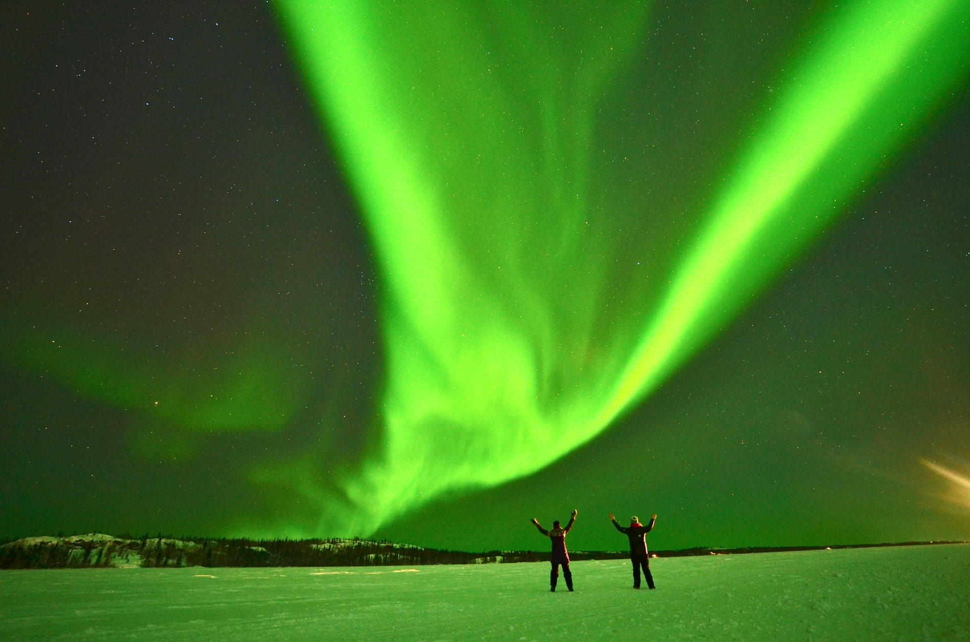 Two people under vibrant northern lights