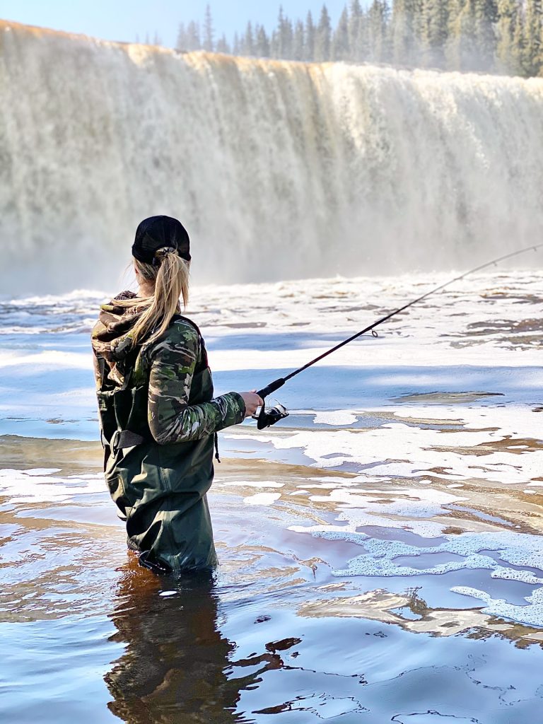Person fishing near a waterfall.
