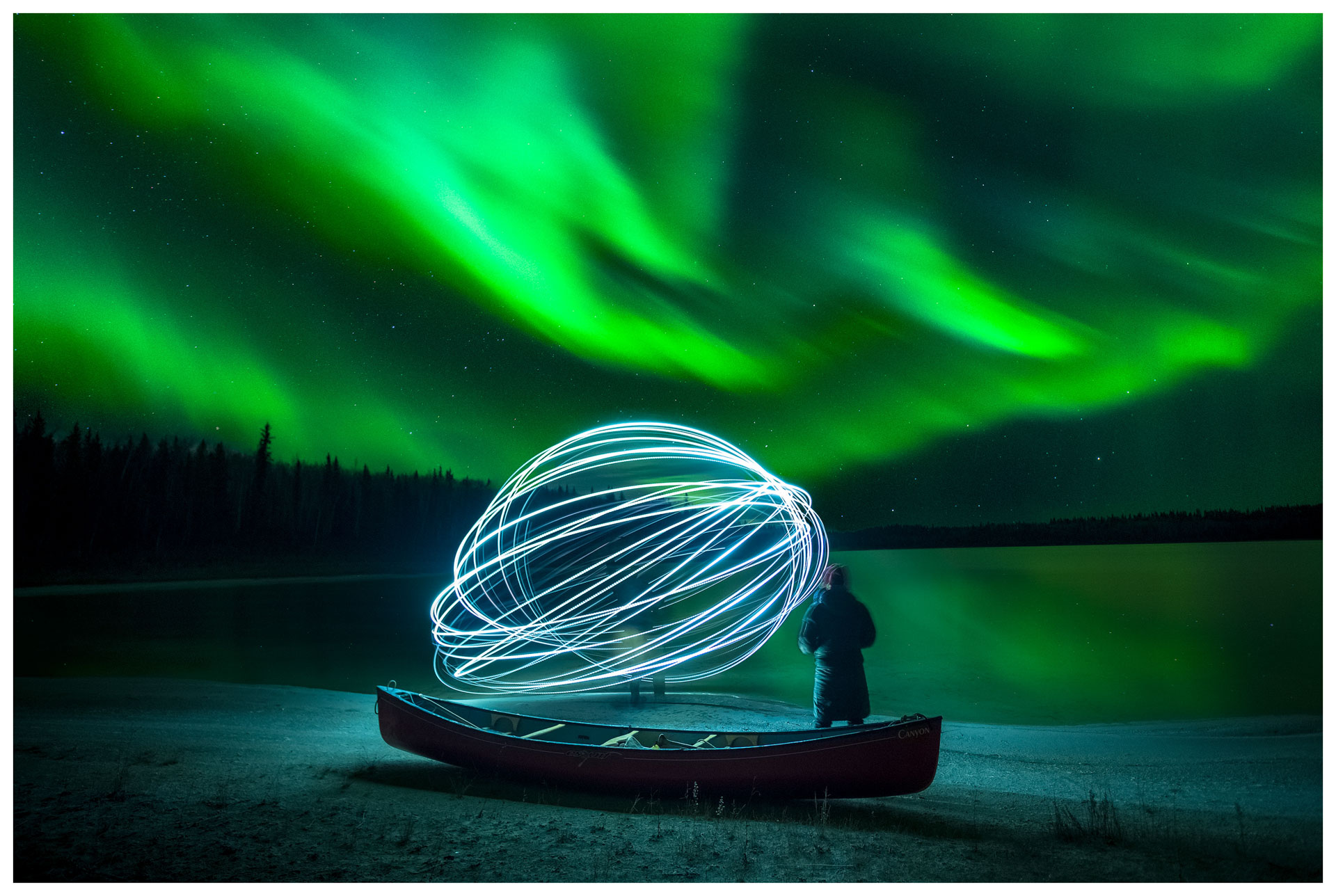 Person with light orb under auroras