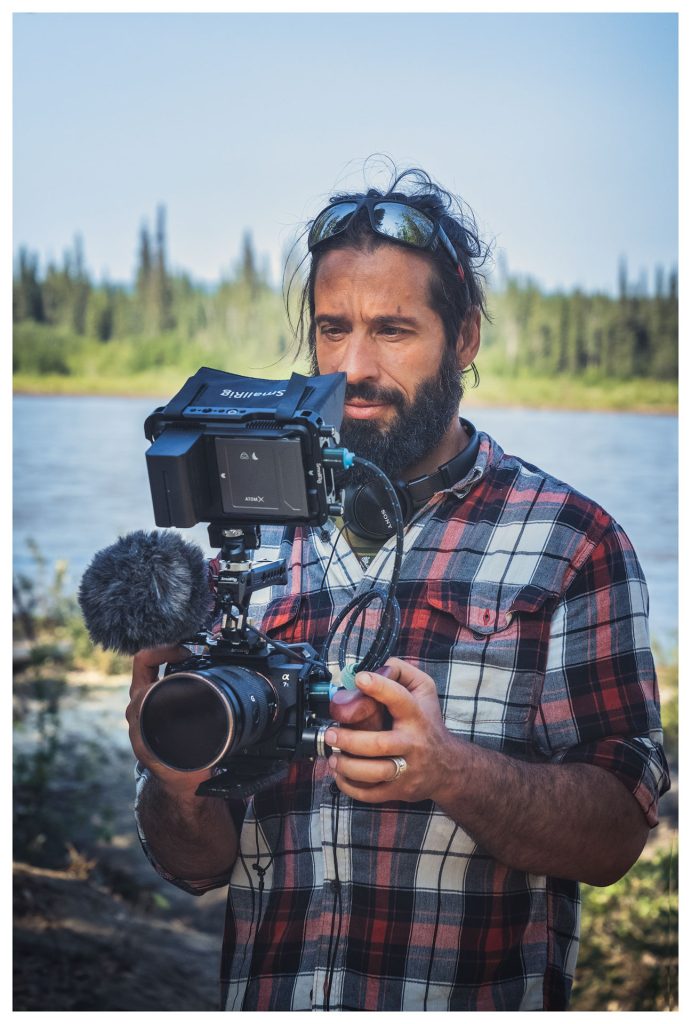 Man filming by the riverbank.
