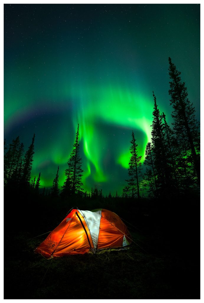 Tent under vibrant northern lights.