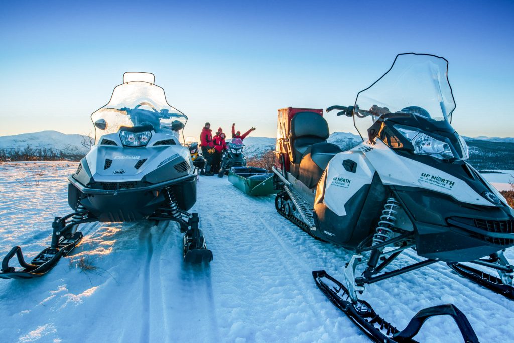 Snowmobiles on snowy landscape at sunset
