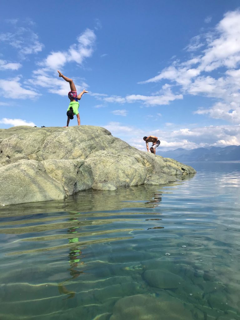 Two people on rocky shoreline, water
