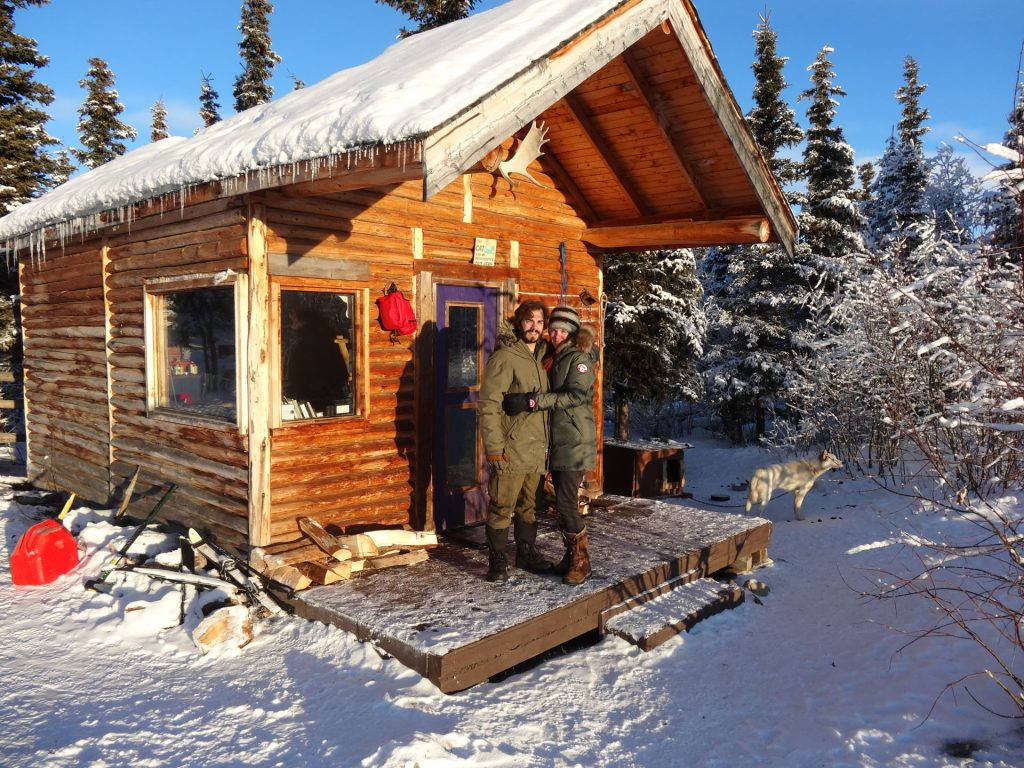 Couple outside cabin in snowy landscape