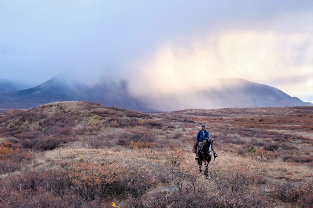 Person riding horse in vast landscape
