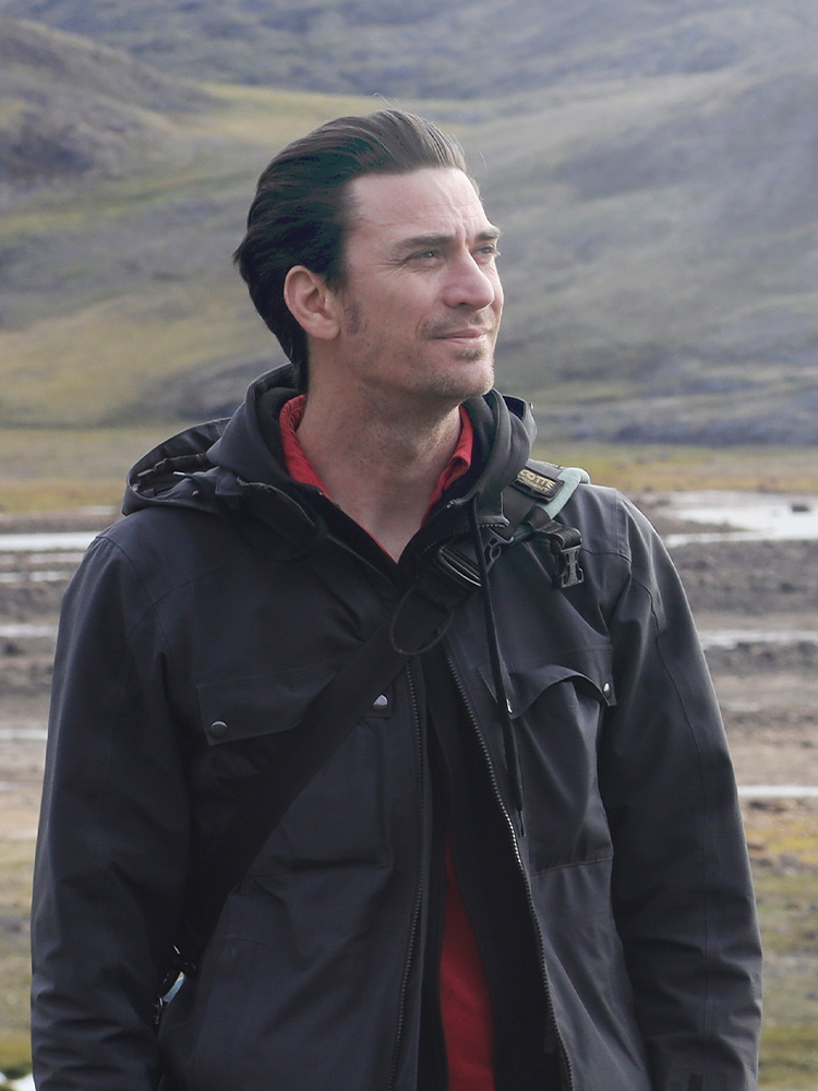 Man in outdoor setting, looking thoughtful.