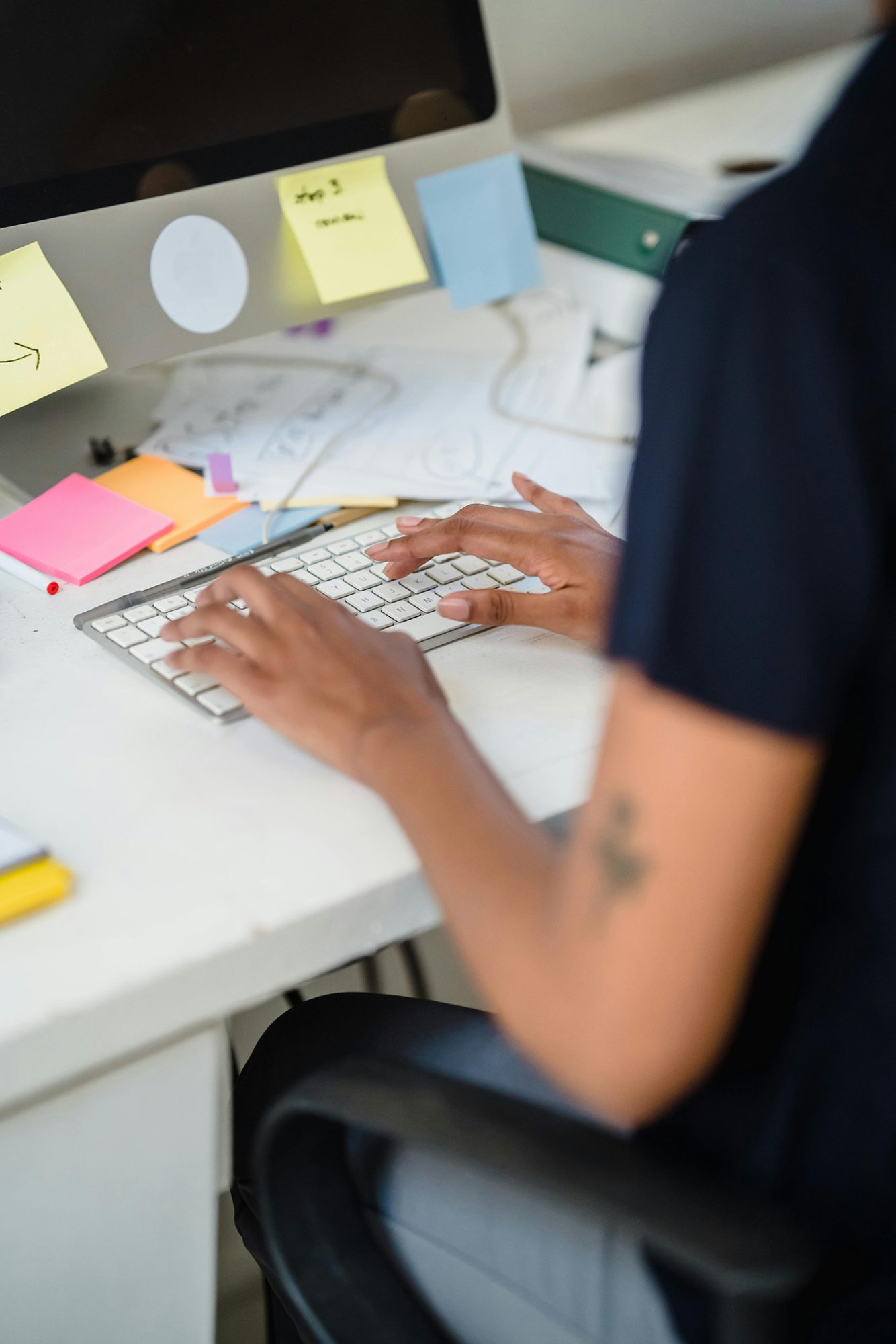 Person typing at a cluttered desk