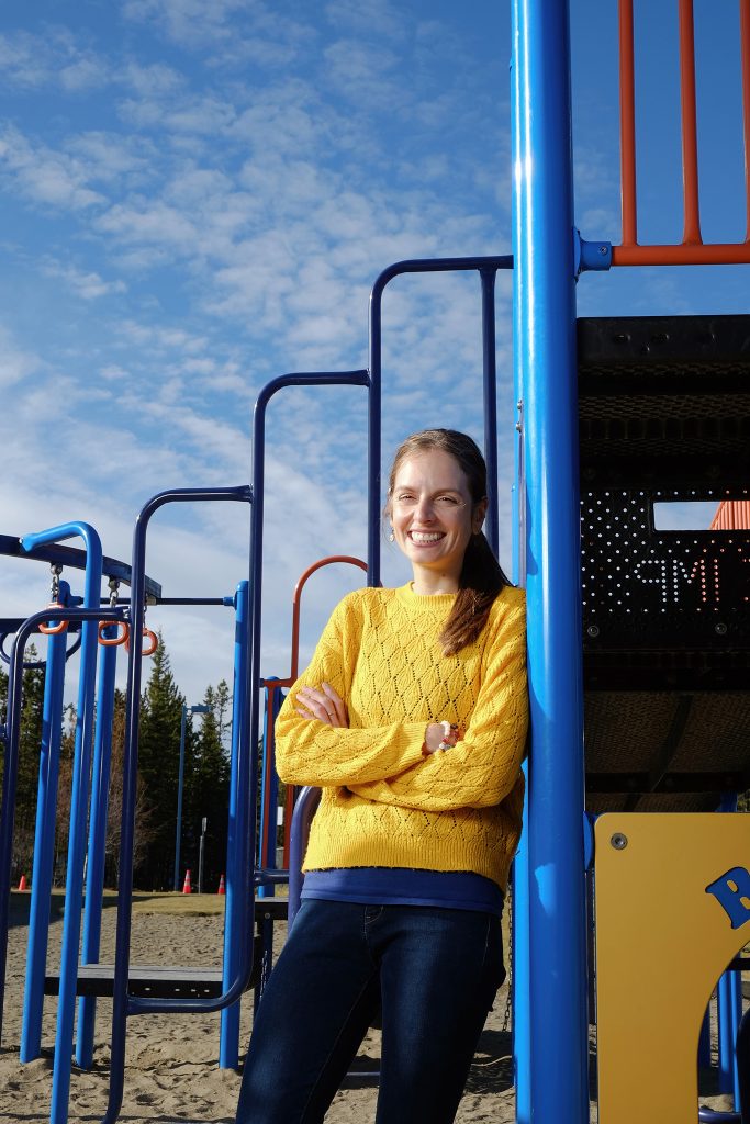 Woman smiling at playground equipment.