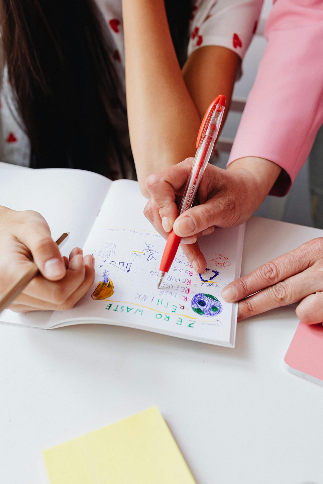 Hands writing in a colorful notebook.