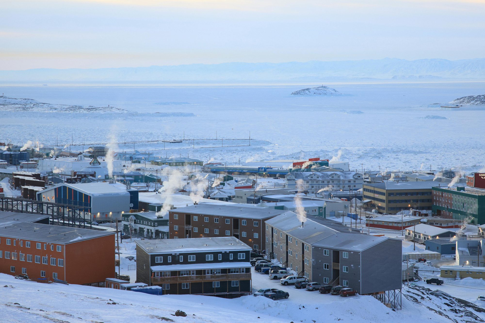 Snowy landscape with buildings and smoke.