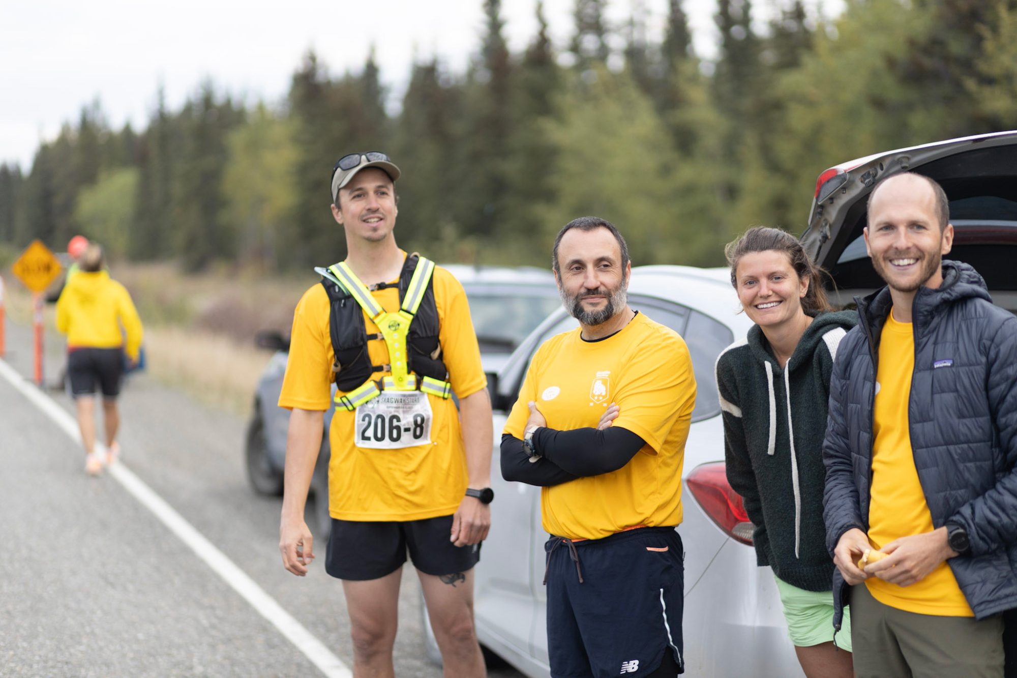 Runners in yellow shirts by car
